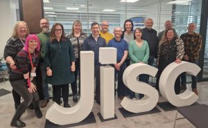 a group of people in an office  standing behind a large white Jisc sculpture 