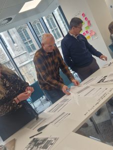 a group of people gathered around a desk looking at sheets of paper